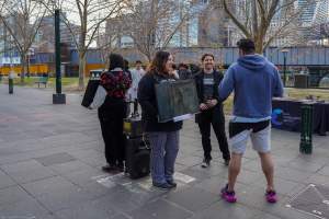 22 June 2025: 5 Question Challenge: Dominion Outreach Melbourne - Animal rights activists participating in a street outreach event in Southbank, Victoria, Australia. Some volunteers hold placards inviting pedestrians to answer 5 questions in exchange for a vegan treat. Others hold TVs showing footage from Farm Transparency Project's dairy investigations. Together, they bring awareness to the hidden reality of what happens to cows, calves, and bulls in the Australian dairy industry. - Captured at VIC.